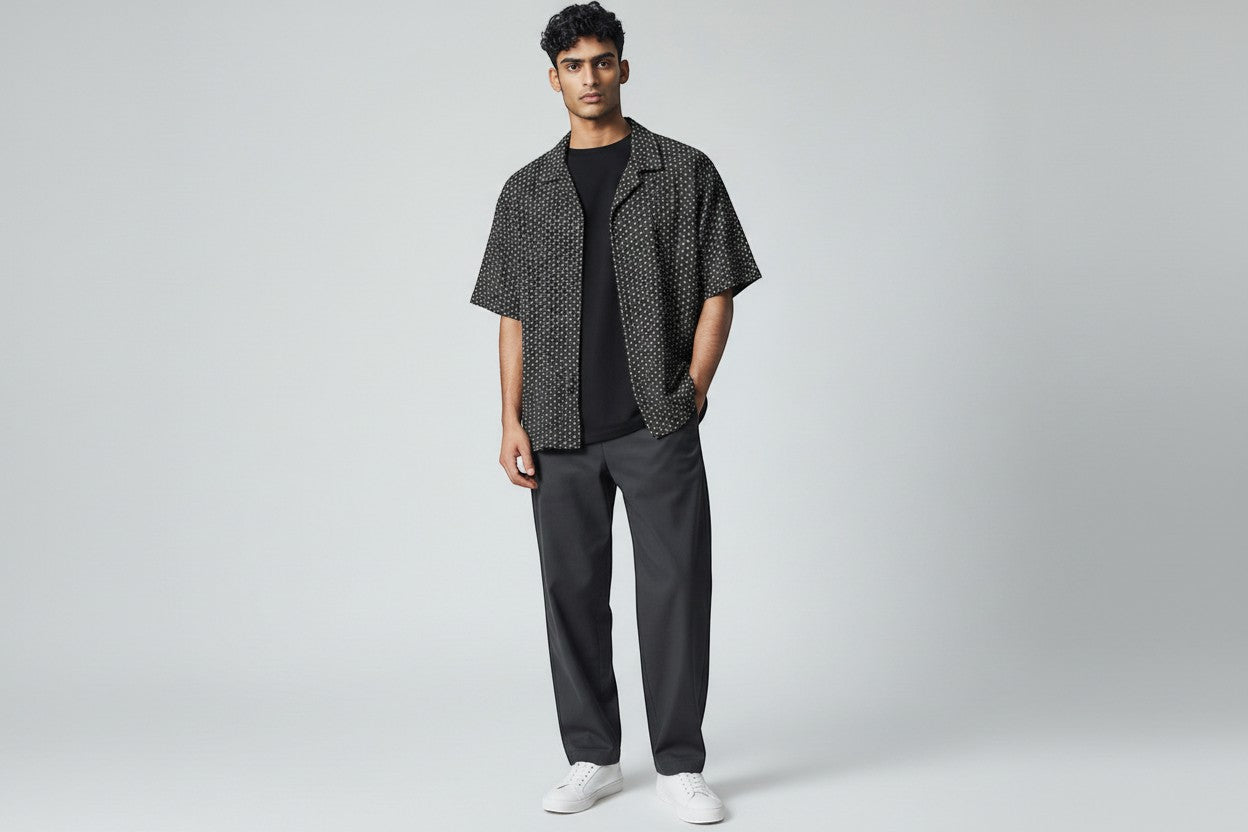 Model wearing an Anchor & Crew black short-sleeve button-down shirt with a white geometric print and camp collar.
