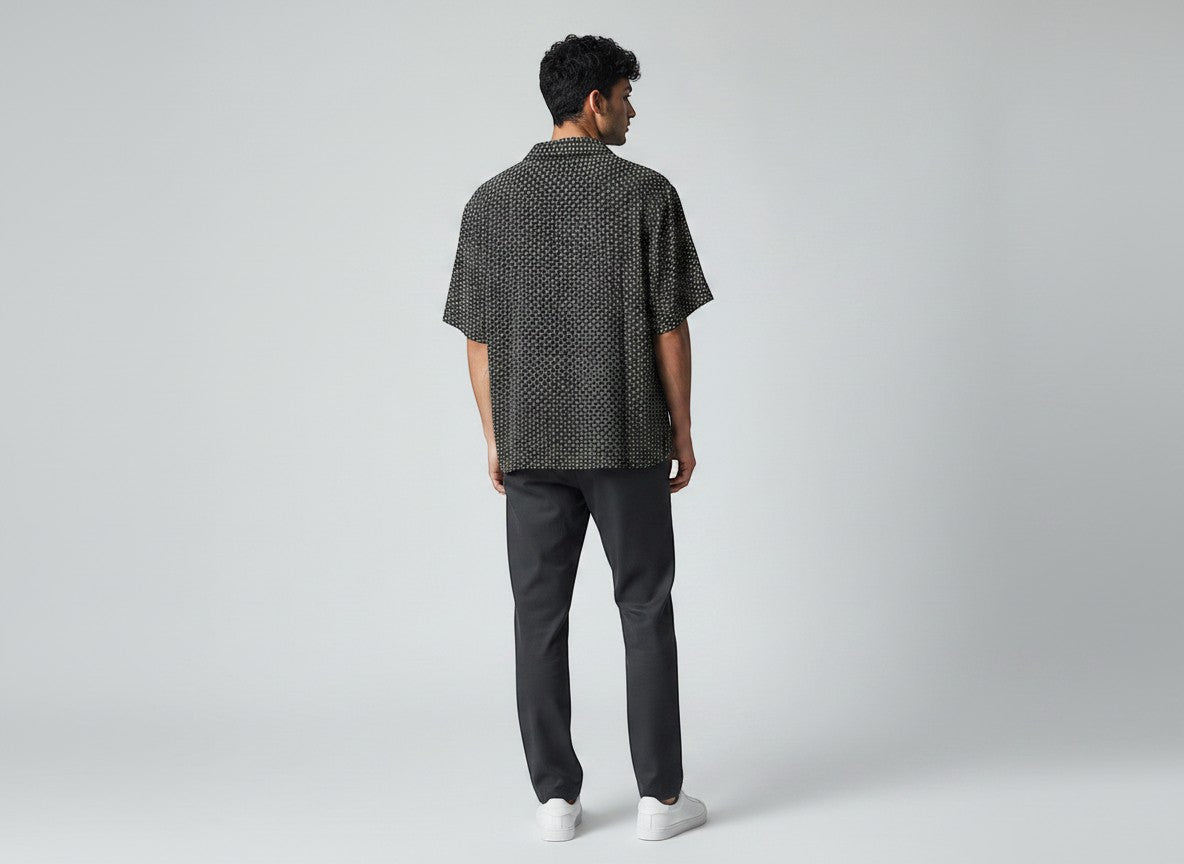 Man wearing an Anchor & Crew black short-sleeve button-down shirt with a white geometric pattern and dark trousers.